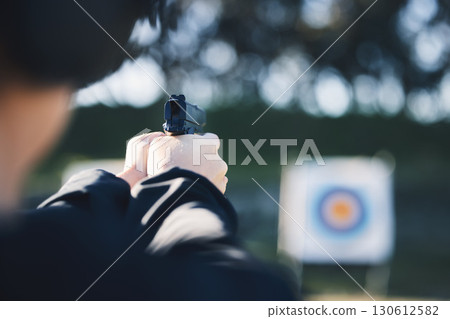 Firearm, target and person training outdoor at shooting range for game exercise or sports challenge closeup. Man hands with gun, circle and aim for practice, police academy or field practice mission Firearm, target and person training outdoor at shooting range for game exercise or sports challenge closeup. Man hands with gun, circle and aim for practice, police academy or field practice mission 130612582