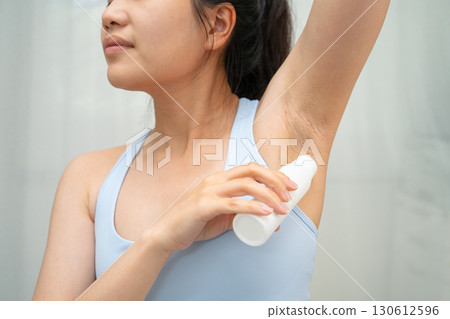 Asian young woman applying roll on deodorant reduce underarm sweat and odor after shower. 130612596