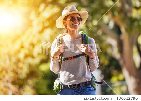 Nature, adventure and woman hiking in a forest for outdoor exercise, wellness and fresh air. Happy, smile and female trekking or walking in a green garden with a backpack and sunglasses in Canada. 130612790