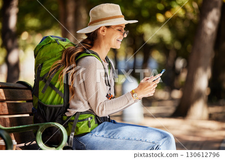 Woman, backpack or phone in travel, sightseeing or adventure in nature park, trees forest or Canada woods. Smile, happy or tourist on mobile technology for gps map, location or hiking path research Woman, backpack or phone in travel, sightseeing or adventure in nature park, trees forest or Canada woods. Smile, happy or tourist on mobile technology for gps map, location or hiking path research 130612796