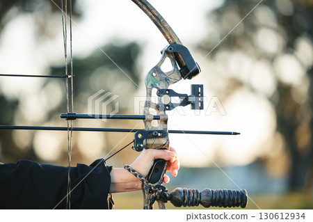 Archery bow closeup and woman hands at shooting range for competition, game or learning in field or outdoor sports. Person with arrow for gaming, adventure and hunting with aim and target practice 130612934