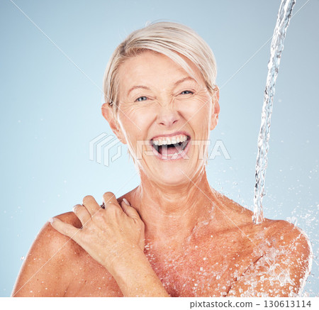 Happy, cleaning and portrait of a woman with a water splash isolated on a blue background in studio. Grooming, hygiene and face of an excited senior model with body and self care on a backdrop 130613114