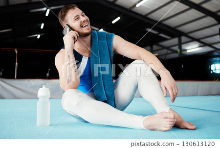 Phone call, fitness and male relaxing after training, workout or competition in arena or studio. Sports, gymnastics and happy man athlete gymnast with a smile on a mobile conversation after practice. Phone call, fitness and male relaxing after training, workout or competition in arena or studio. Sports, gymnastics and happy man athlete gymnast with a smile on a mobile conversation after practice. 130613120