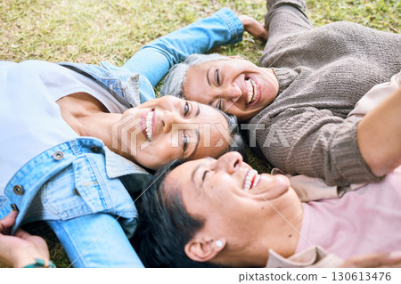Elderly, happy or friends on grass in a park talking or speaking of funny gossip relaxing holiday vacation in summer. Smile, old people or senior women laughing at a crazy joke or bonding in nature 130613476