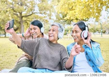 Headphones, friends phone selfie and women at park taking pictures for social media. Mobile, retirement and group of senior females streaming music, taking photo and laughing at comic meme or joke. 130613496