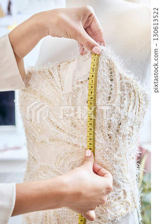 Hands, fashion and measuring tape by woman designer for dress, pattern and details of fabric in studio. Creative, girl and measurement by dressmaker working on luxury, elegant and classic clothing 130613522