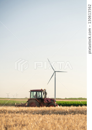Agricultural tractor is working on the field with wind turbines Agricultural tractor is working on the field with wind turbines 130613562