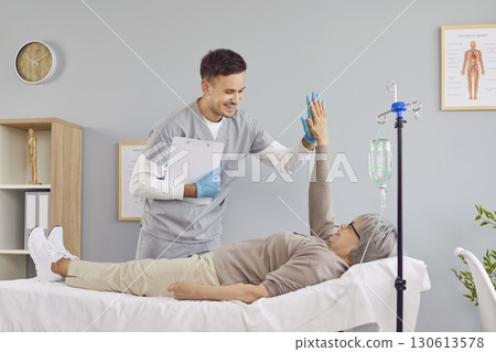 Friendly nurse supporting senior patient who is receiving intravenous vitamin infusion 130613578