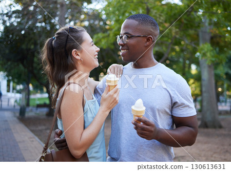 Love, ice cream or couple of friends hug in a park on a romantic date in nature in an interracial relationship. Bonding, relaxed black man and happy woman enjoying a snack on a fun holiday vacation 130613631