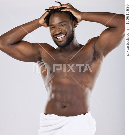 Black man in towel and skin in portrait, shower and hygiene, grooming and beauty isolated on studio background. Smile, muscle and abs, strong and skincare glow, body care with natural cosmetics Black man in towel and skin in portrait, shower and hygiene, grooming and beauty isolated on studio background. Smile, muscle and abs, strong and skincare glow, body care with natural cosmetics 130613650
