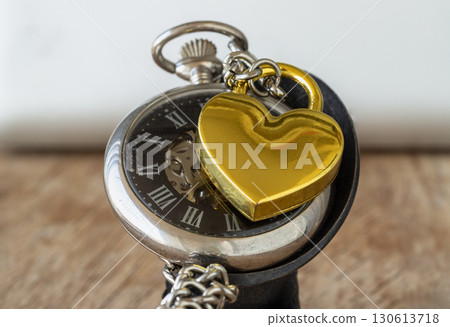 A elegance of Golden heart shaped love padlock on A retro pocket watch. A elegance of Golden heart shaped love padlock on A retro pocket watch. 130613718