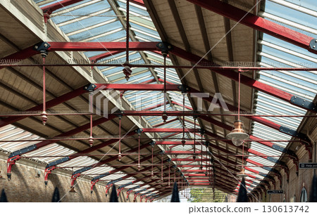 A vintage copper ceiling light fixture with a glass globe shade hangs from a white ceiling and Wooden beams. 130613742