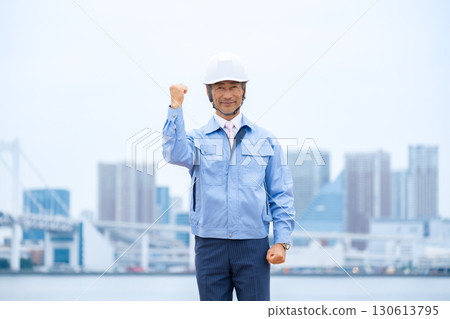穿著工作服的男人，戴著頭盔，天空，拳頭 130613795