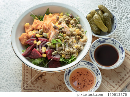 Colorful poke bowl with Quinoa, Salmon mix Leaves salad, Beetroot, Sweet potato sprinkle with Sweet corn and Pistachio Served with Pickled Cornichons, Balsamic vinegar and Chilli oil. 130613876