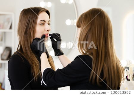Makeup Artist Applying Lipstick to Client Makeup Artist Applying Lipstick to Client 130613892