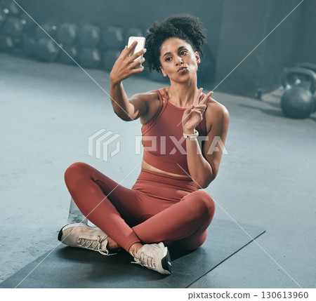 Fitness, selfie and woman on a gym floor with phone, peace and hand sign before exercise routine. Workout, picture and peace gesture by black woman posing for photo after training, emoji and relax Fitness, selfie and woman on a gym floor with phone, peace and hand sign before exercise routine. Workout, picture and peace gesture by black woman posing for photo after training, emoji and relax 130613960