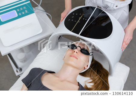 Beautician using led light therapy facial device on client for skin rejuvenation Beautician using led light therapy facial device on client for skin rejuvenation 130614110