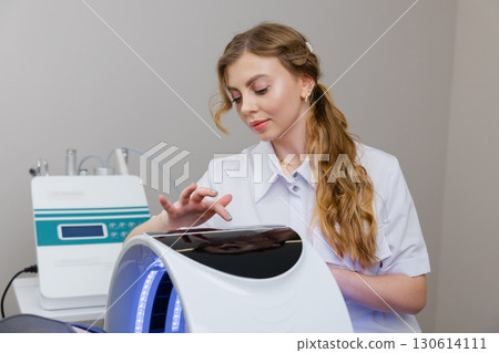 Beautician using led light therapy machine for skin rejuvenation 130614111