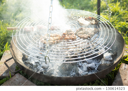 Meat and kebabs grilling on barbecue over hot coals 130614323