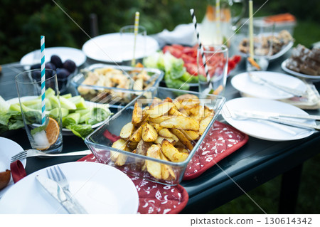 Baked potato wedges served in glass dish on picnic table Baked potato wedges served in glass dish on picnic table 130614342