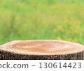 Natural wooden empty tree stump table top, round podium with green blurred background. Tree trunk wood Podium display for food and products on nature background. Rustic Tree Stump in Lush Green 130614423