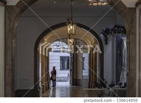 Side view A woman standing and looking at showcase the products on display in building with Beautiful antique lantern hanging from ceiling. Side view A woman standing and looking at showcase the products on display in building with Beautiful antique lantern hanging from ceiling. 130614850