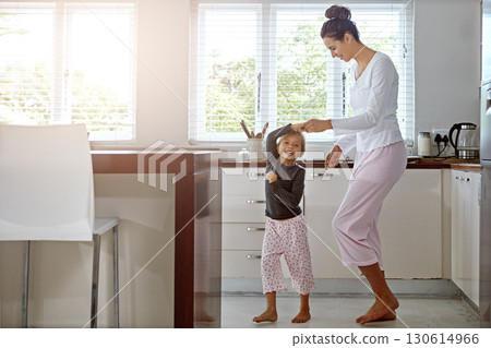 Kitchen dance, mom and girl in the morning at home with happiness dancing together. Mom, child and mama care holding hands with a young kid in a house happy about funny family with a smile 130614966