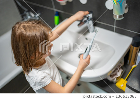 Little girl brushing her teeth with an electric toothbrush in the bathroom in the morning. Concept of personal hygiene and daily morning routine in childhood. 130615065