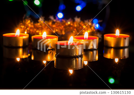 In the dark space, dozens of candles burn, giving off a gentle glow In the dark space, dozens of candles burn, giving off a gentle glow 130615130