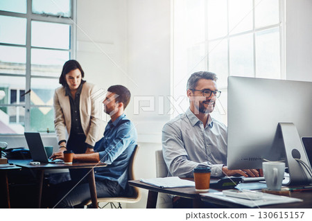 Office, computer and businessman with his colleagues talking or discussing in the background. Pc, success and mature professional male employee working on a corporate company report in the workplace. 130615157
