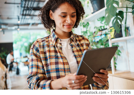 A young woman uses a tablet in a stylish cafe that inspires creativity and connection 130615306