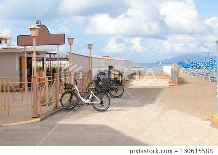Wooden structures, changing room on beach. Bicycle near sea. Nature and sea. Vacation and rest in summer. Sunny day and blue sky. Wooden structures, changing room on beach. Bicycle near sea. Nature and sea. Vacation and rest in summer. Sunny day and blue sky. 130615588