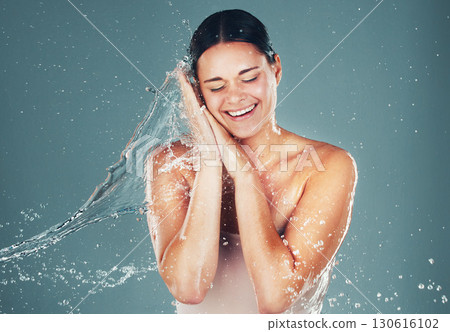 Water, wellness and cleaning with a woman in studio on a blue background for hygiene or hydration in the shower. Spa, splash and beauty with an attractive young female washing in the bathroom 130616102