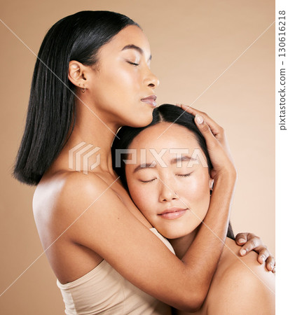 Beauty, love and diversity with a model woman friends in studio on a beige background for natural skincare. Spa, health and wellness with an attractive young female holding the head of her friend Beauty, love and diversity with a model woman friends in studio on a beige background for natural skincare. Spa, health and wellness with an attractive young female holding the head of her friend 130616218