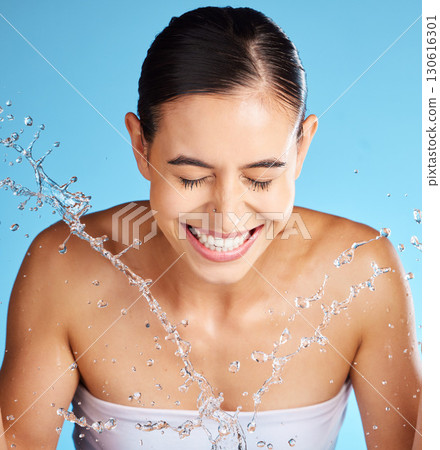 Face wash, skincare and woman isolated on blue background for beauty, cosmetics cleaning and happy. Smile of a person or model with water splash for dermatology wellness and aesthetic in studio 130616301