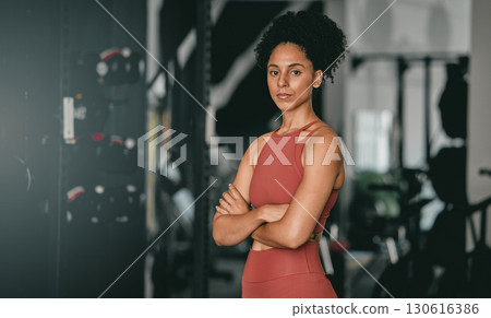 Black woman, fitness and coach with arms crossed for workout, training or exercise standing in the gym. Portrait of a confident African American female sports instructor with vision for healthy body 130616386