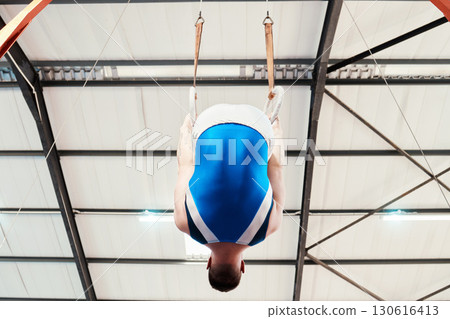 Man, acrobat and gymnastics on rings in fitness for practice, training or workout performance at gym. Professional male gymnast hanging on ring circles for athletics, acrobatics or strength exercise Man, acrobat and gymnastics on rings in fitness for practice, training or workout performance at gym. Professional male gymnast hanging on ring circles for athletics, acrobatics or strength exercise 130616413