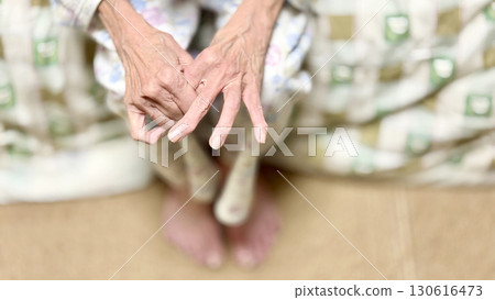 An elderly woman wearing pajamas massaging the fingers of both hands An elderly woman wearing pajamas massaging the fingers of both hands 130616473
