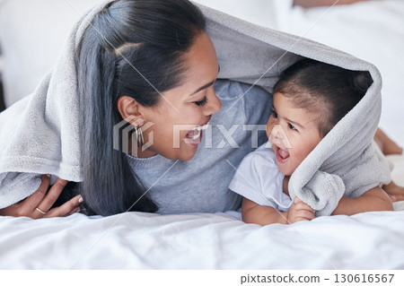 Mother, parent and baby playing or bonding in a bed with blanket laughing being funny together in a bedroom or room. Mom, kid and single mum in a home or house with little daughter or child Mother, parent and baby playing or bonding in a bed with blanket laughing being funny together in a bedroom or room. Mom, kid and single mum in a home or house with little daughter or child 130616567