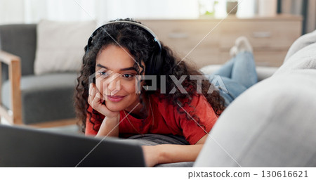 Headphones, laptop and streaming with woman on sofa in living room of home for online subscription. Computer, relax and watching video with person in apartment for break, entertainment or media 130616621