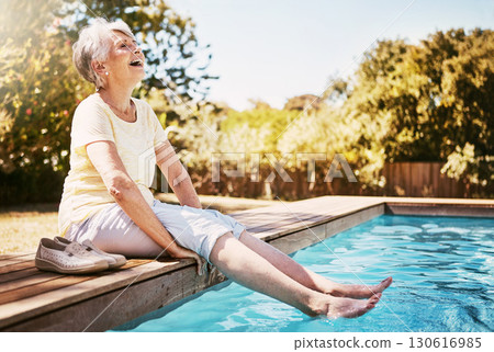 Elderly woman with her feet in the water of the pool while on a vacation, adventure or outdoor trip in summer. Happy, smile and senior lady in retirement relaxing by swimming pool at a holiday resort 130616985