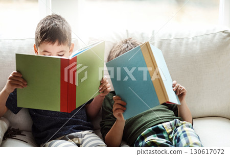 Children, bonding and reading books for education, learning or relax studying on house living room in family home sofa. Kids, brothers and boys with storytelling, fairytale novels or fantasy fiction 130617072