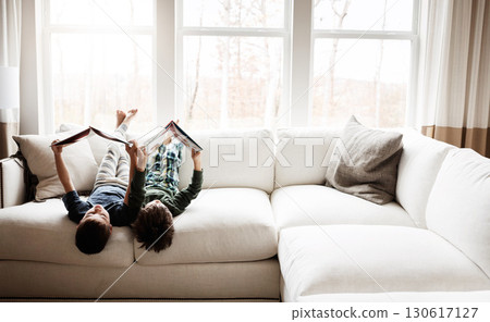 Fun children, bonding and reading books in education, learning or relax studying upside down on house living room or sofa. kids, storytelling and fantasy fairytale novel in creative home inspiration 130617127