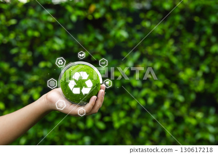 Hand holding green recycle symbol globe with eco icons on natural background, representing sustainability, environmental conservation, and eco-friendly renewable energy concept. Hand holding green recycle symbol globe with eco icons on natural background, representing sustainability, environmental conservation, and eco-friendly renewable energy concept. 130617218