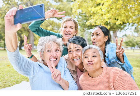 Senior people, friends and phone for selfie at the park together with smile and peace sign in the outdoors. Happy group of silly elderly women smiling for photo looking at smartphone in nature 130617251