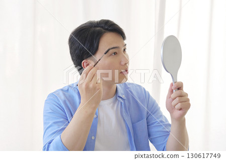 Man in his 20s drawing his eyebrows 130617749