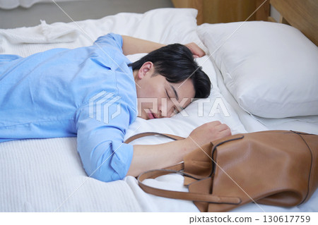 A tired man sleeping in bed in casual clothes 130617759