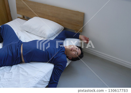 A man in his 20s sleeping in bed with a bad posture 130617783