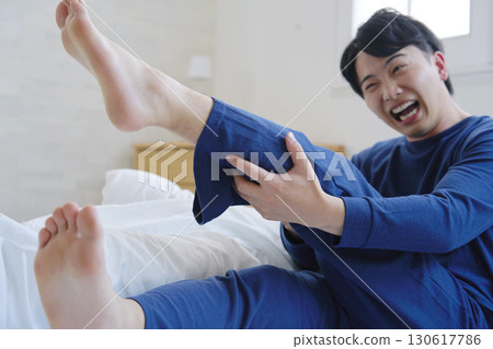 A man in his 20s with leg cramps in bed 130617786