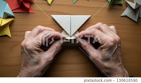 Hands Creating White Origami Paper Craft on Wooden Table	 130618580